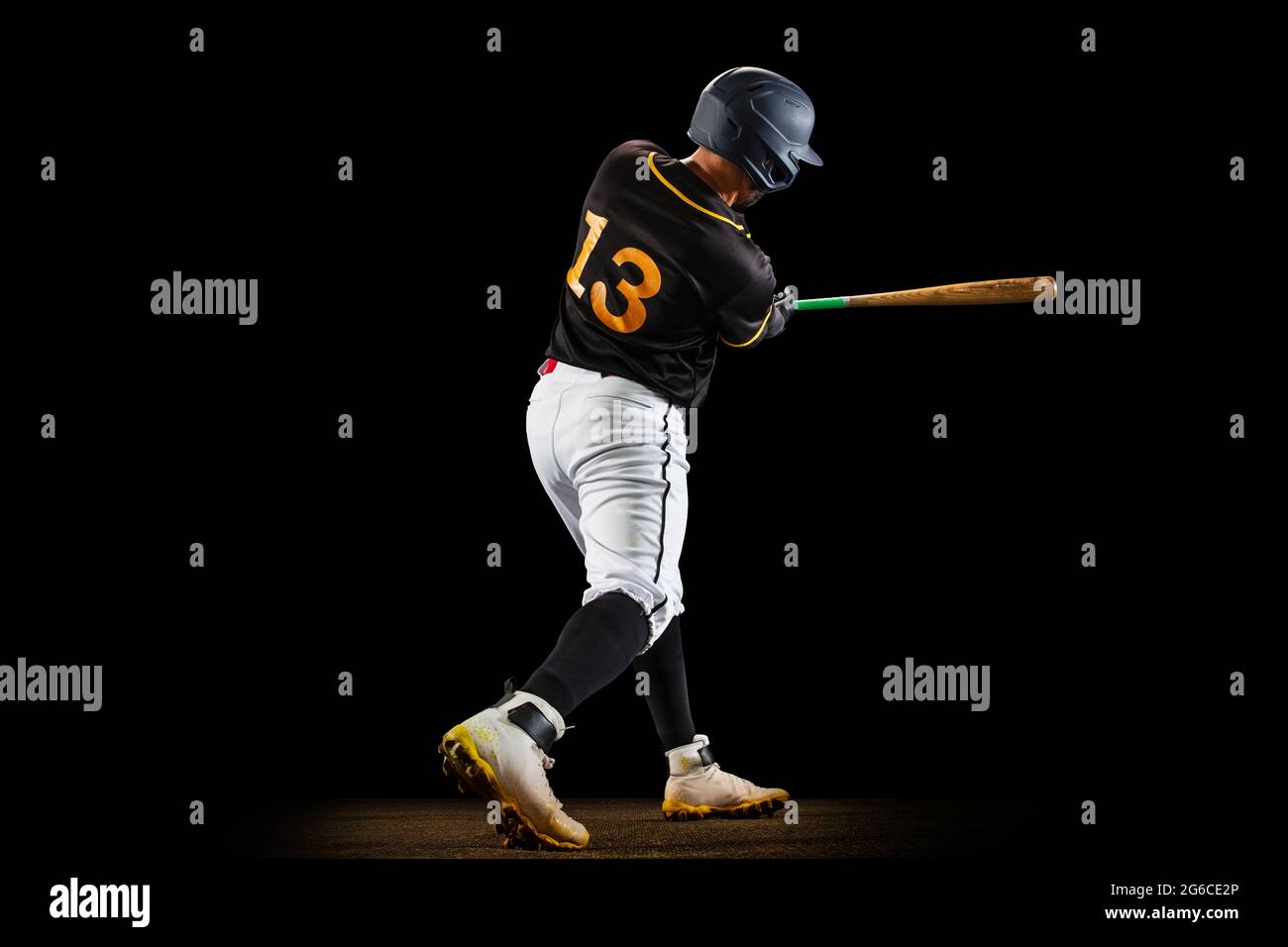 Professional baseball player, pitcher in sports uniform and equipment playing baseball isolated on black studio background in neon light. Rear view Stock Photo
