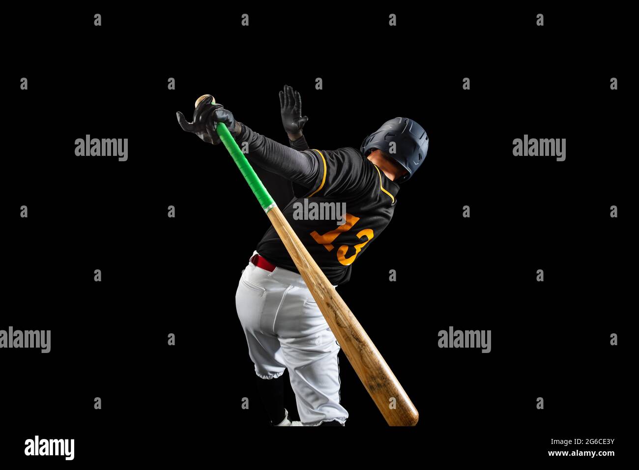 Professional baseball player, pitcher in sports uniform and equipment playing baseball isolated on black studio background in neon light. Rear view Stock Photo