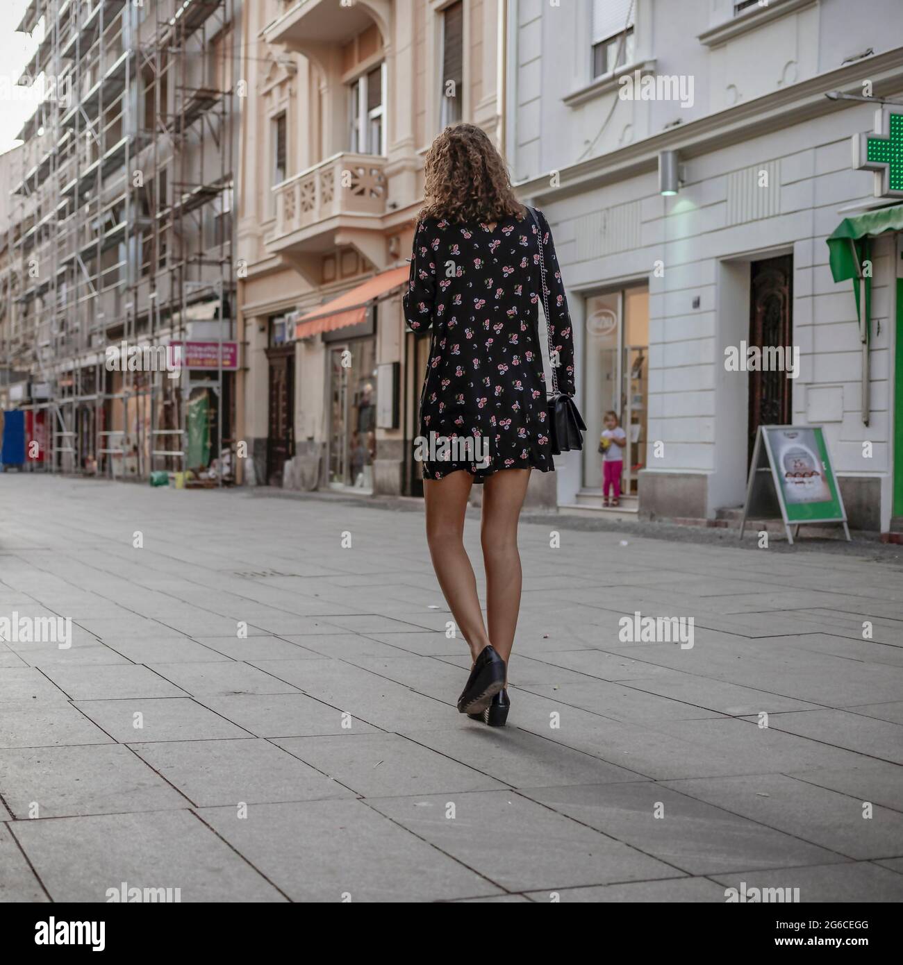 Urban scene with a slender woman walking down the street Stock Photo