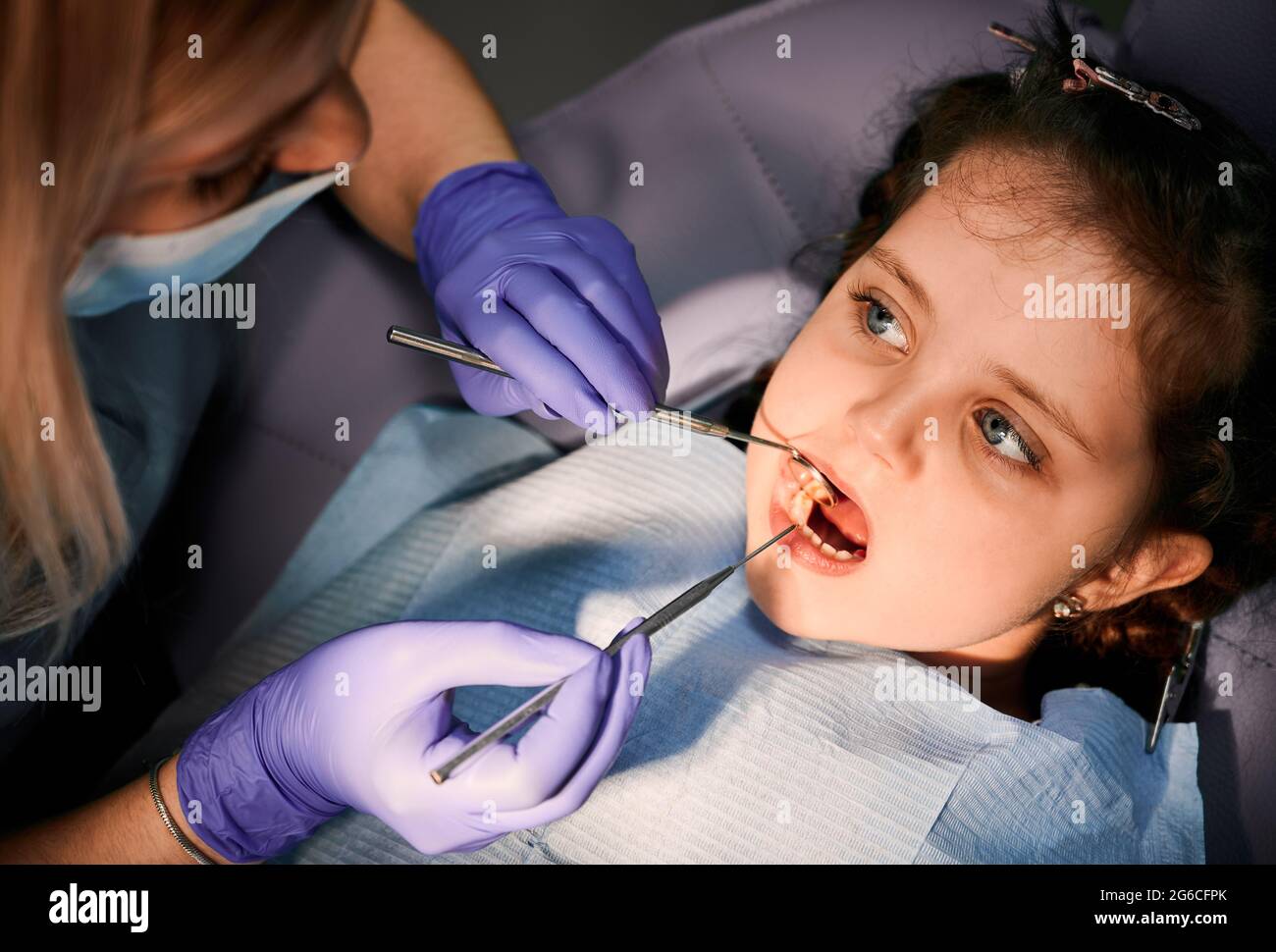 Close up of adorable little girl with open mouth while dentist checking
