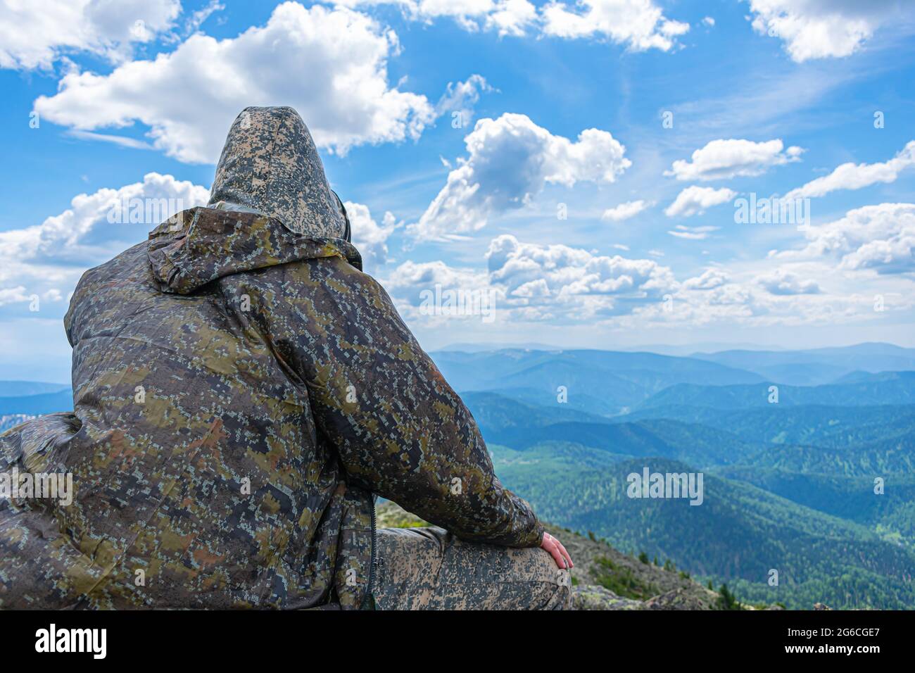 Lonely man sitting on the top of the mountain, resting and enjoying the ...