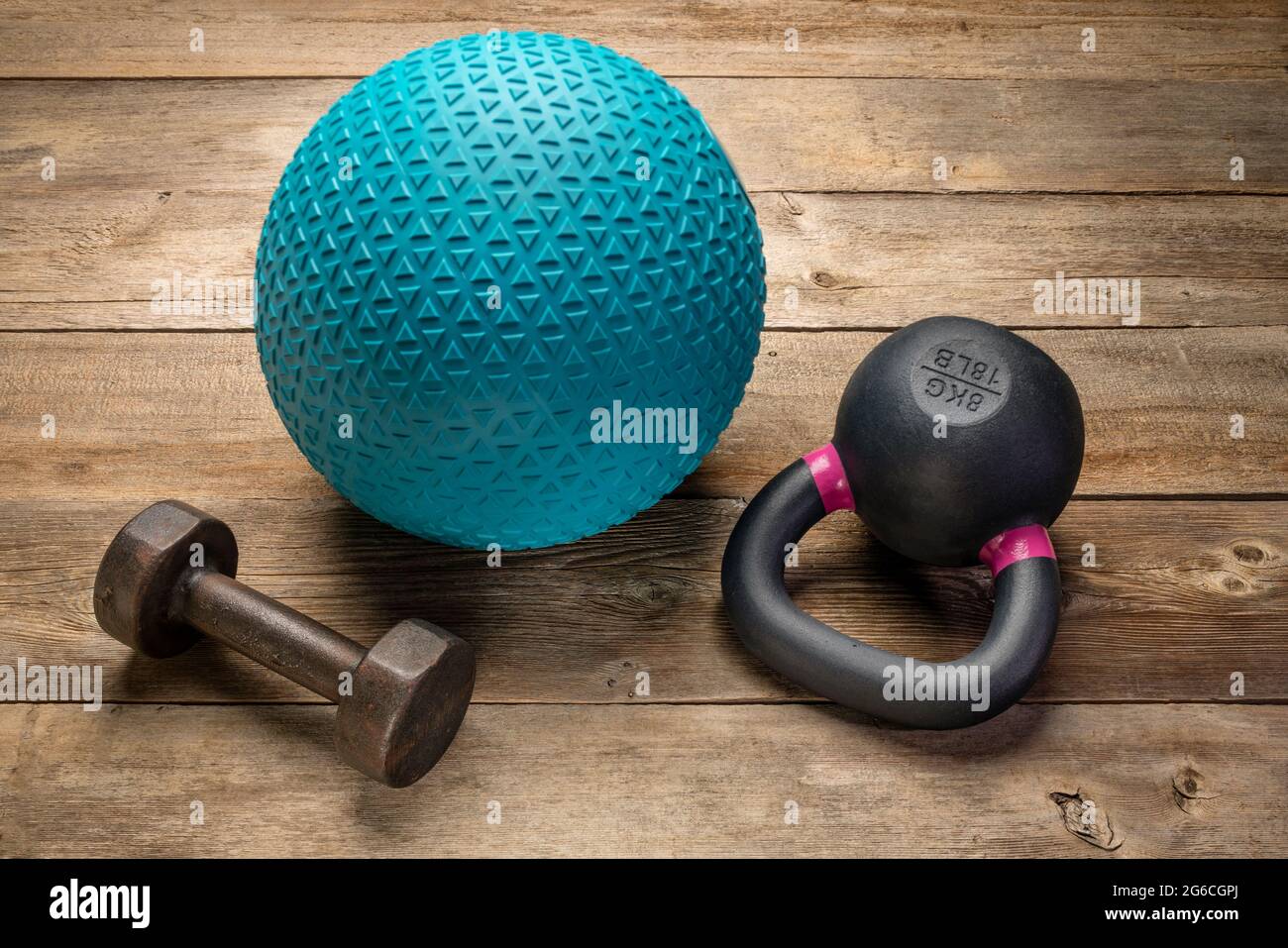 heavy rubber slam ball filled with sand small iron kettlebell and a dumbbell on a rustic wood background training exercise and fitness concept Stock Photo Alamy