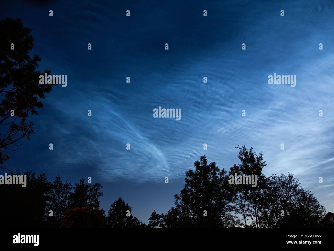 Noctilucent clouds or night shining clouds in midnight summer sky. Glowing white clouds in upper atmosphere where sun still shines on them. Stock Photo
