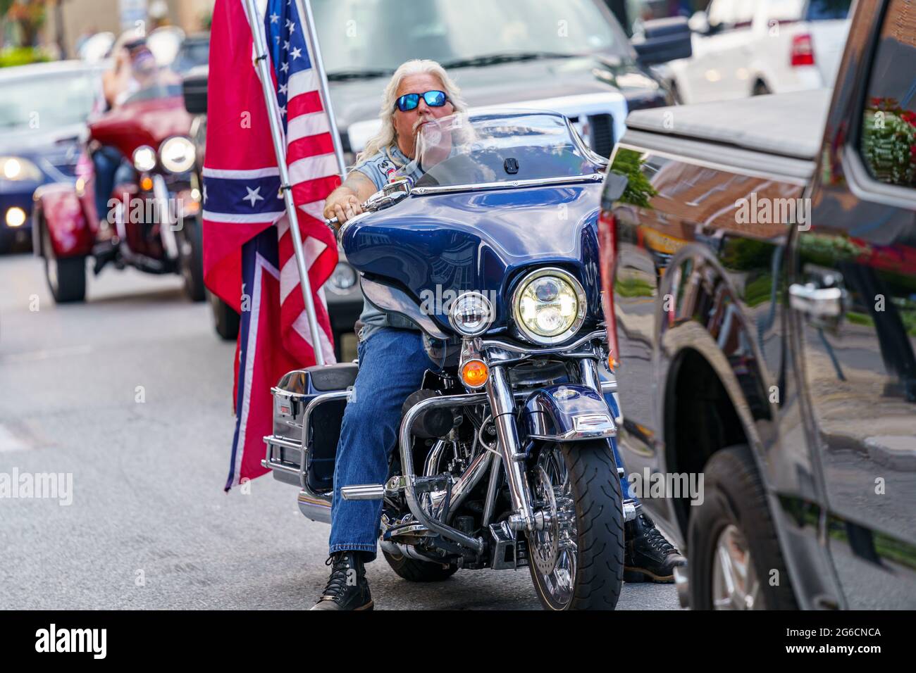 Gettysburg, PA, USA - July 4, 2021: A motorcyclist in the downtown area displaying bot the US and Confederate flags. Stock Photo
