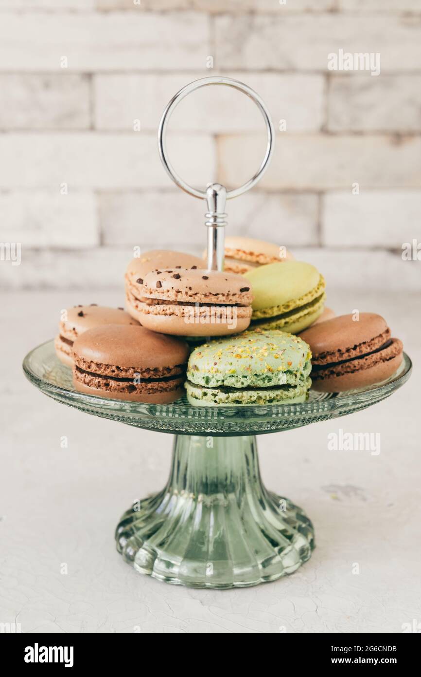 Colourful french macarons on a glass etagere in front of a white wall.  Pastries, desserts and sweets. Vertical stock photo Stock Photo - Alamy
