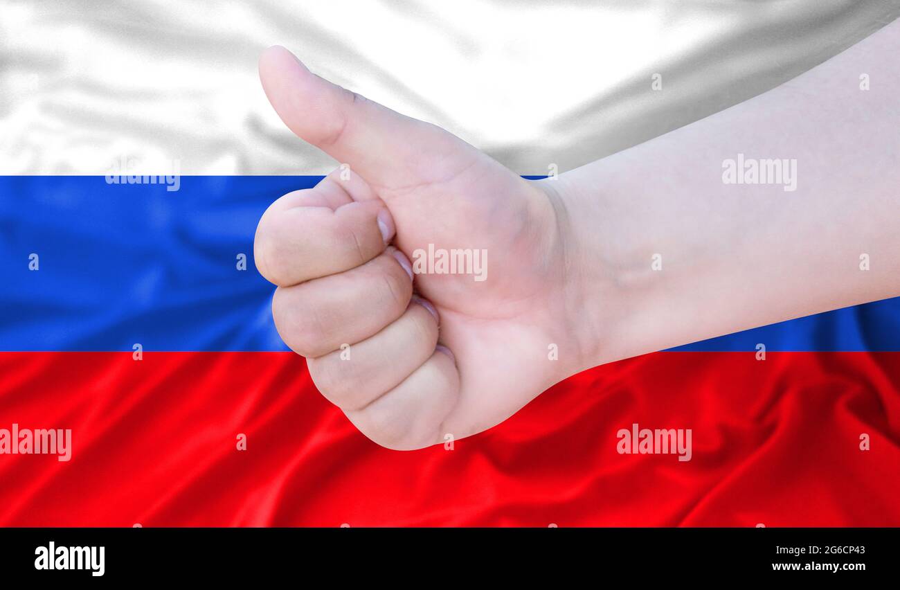 Hand makes a thumbs up sign on the background of the flag of Russia ...