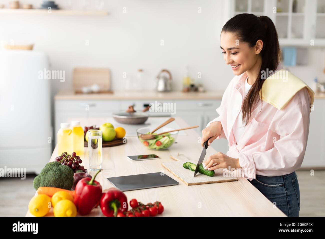 Woman cooking salad and using tablet at kitchen Stock Photo