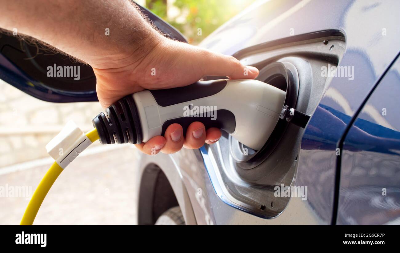 The electric car charger plugged in to the socket.The modern electric car charging the battery. Stock Photo