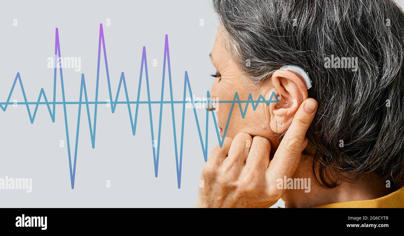 Hearing aids. Senior woman wearing behind the ear hearing aid with