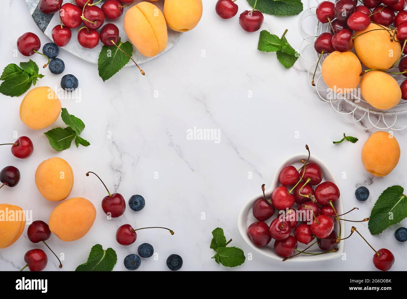 Fresh apricots, red cherry and blackberry on white marble background. Vegetarian, weight loss, clean and healthy eating concept. Top view. Copy space. Stock Photo