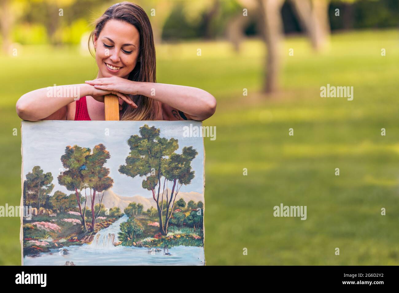 Woman sitting behind a canvas painted outdoors Stock Photo