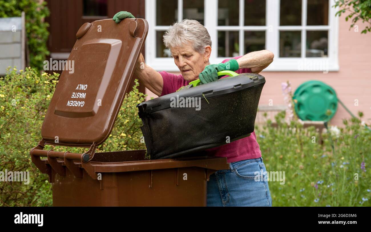Hampshire, England, UK. 2021. Woman emptying grass cuttings into a