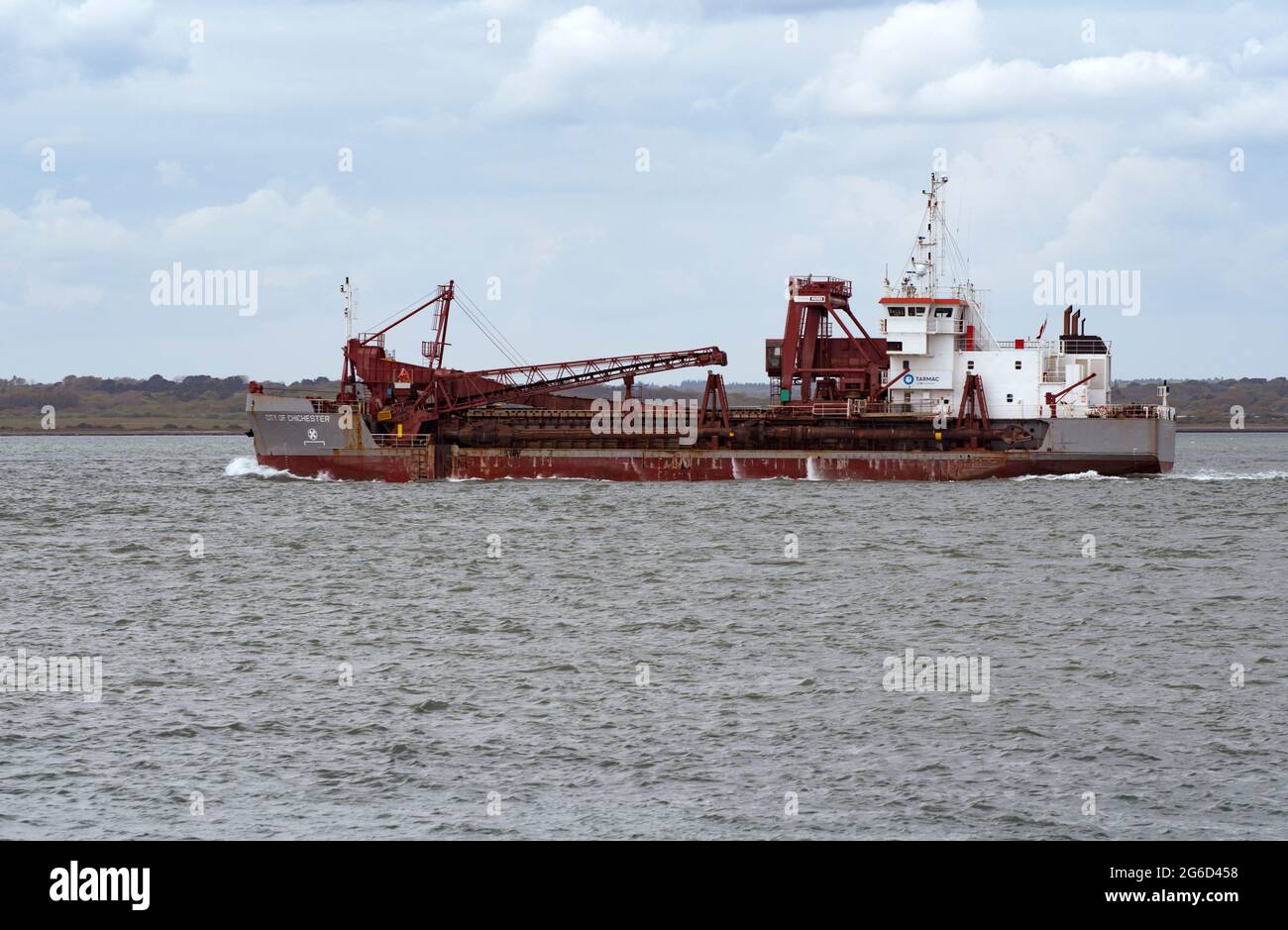 The City of Chichester Dredger heading towards Southampton Docks, passing Hurst Castle and the Lighthouse western entrance to the Solent. Stock Photo