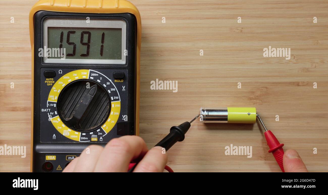 Testing AA battery cell with digital multimeter tool voltage check showing good value battery is still new and full charge Stock Photo Alamy