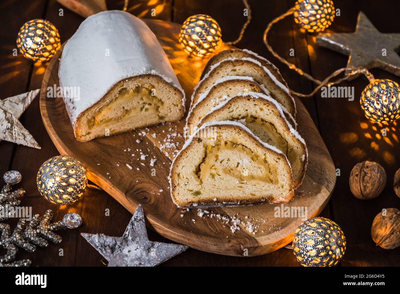 Christmas stollen on a wooden board, lights and christmas decoration in the wooden background, traditional german christmas cake Stock Photo
