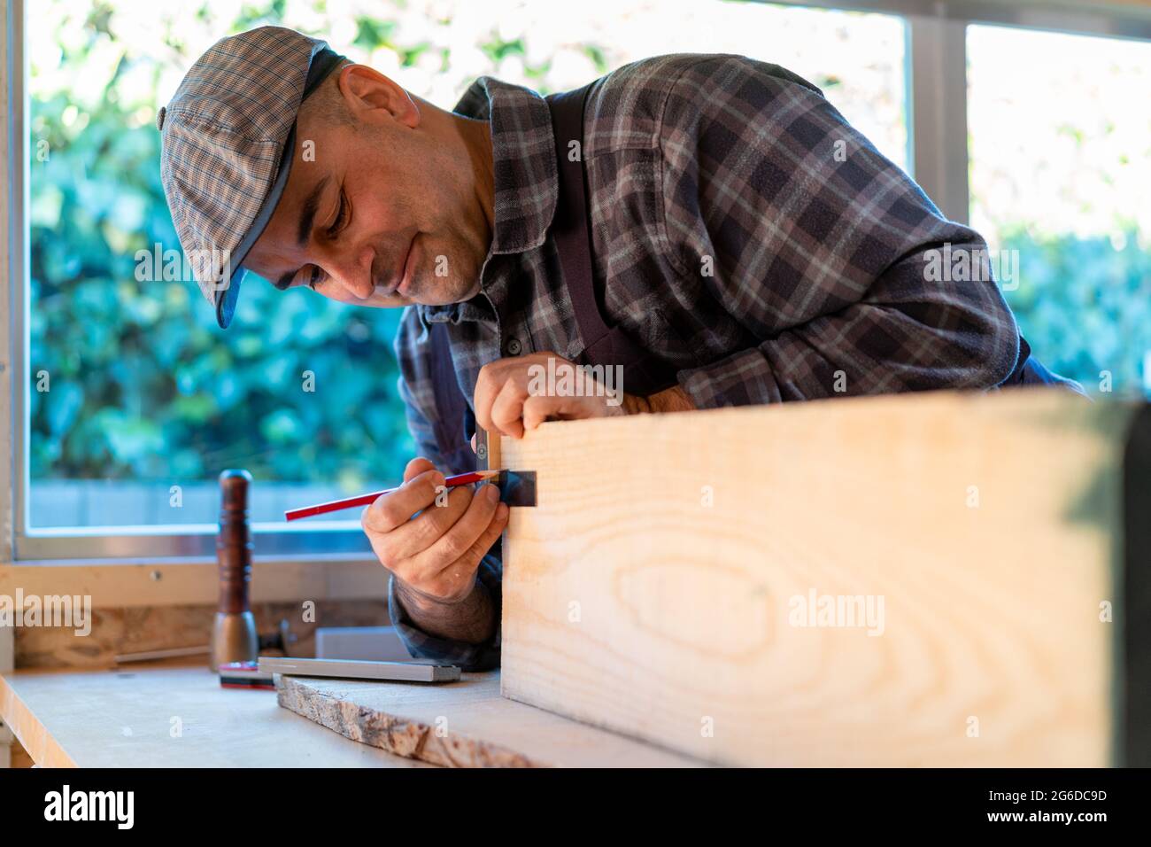 Positive professional woodworker with pencil and measuring tool making