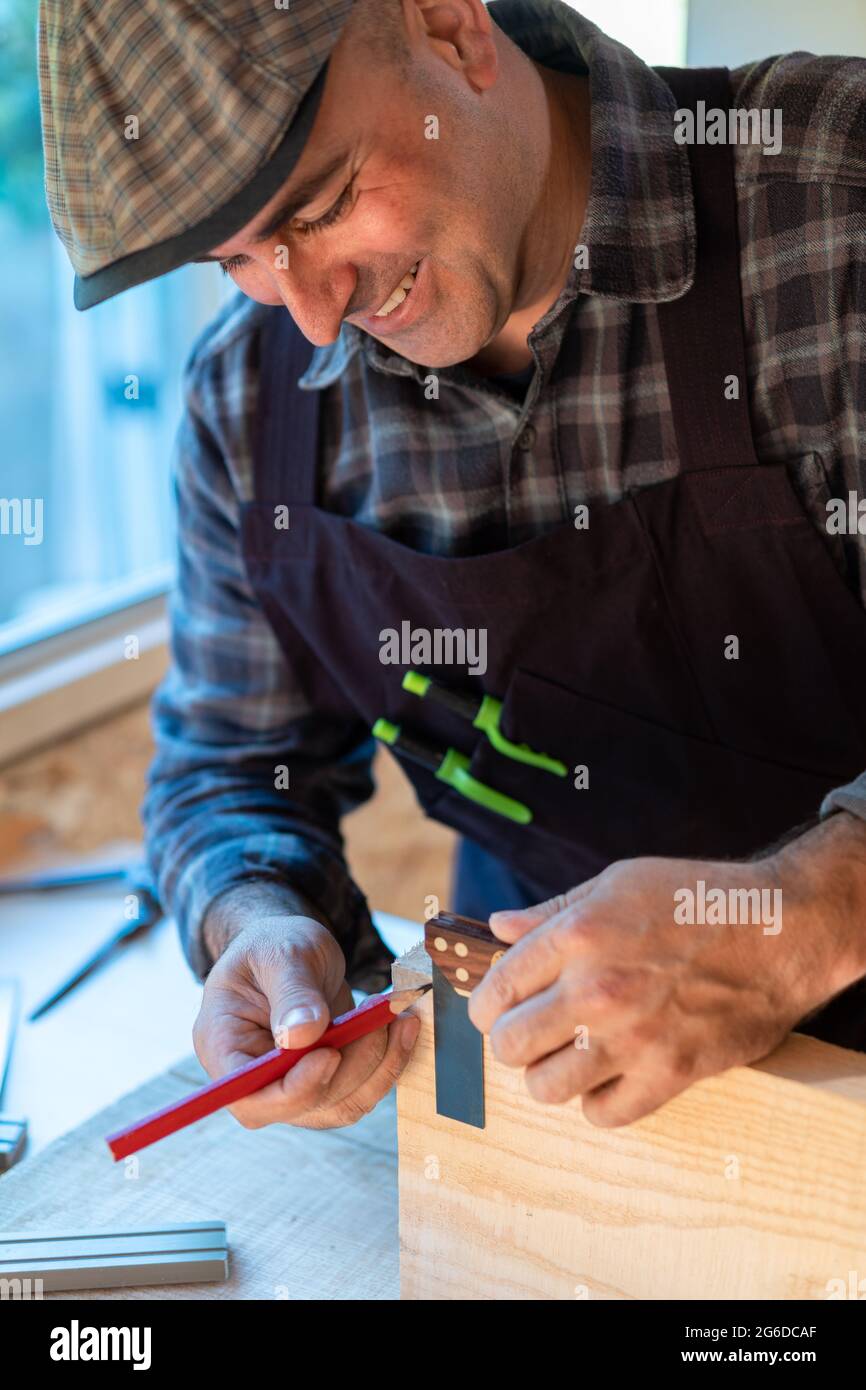 Positive professional woodworker with pencil and measuring tool making