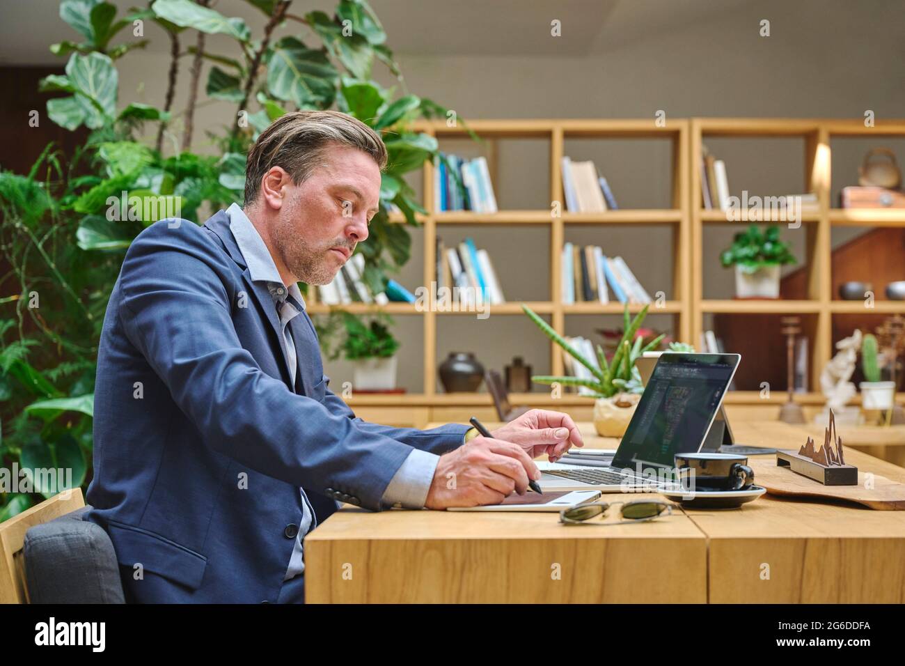 Designer at his desk working on his computer using his tablet Stock Photo