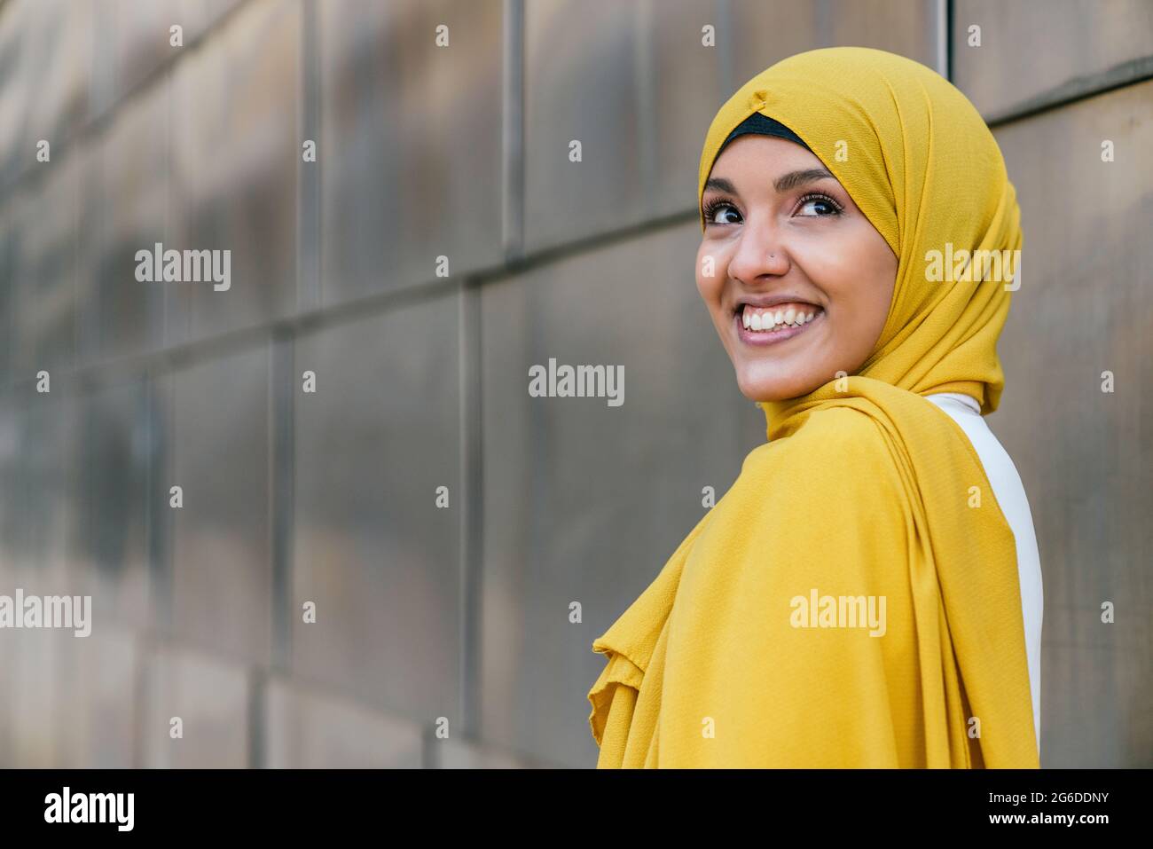 Side View Of Trendy Muslim Female In Yellow Hijab Standing In Street And Looking Away Stock 
