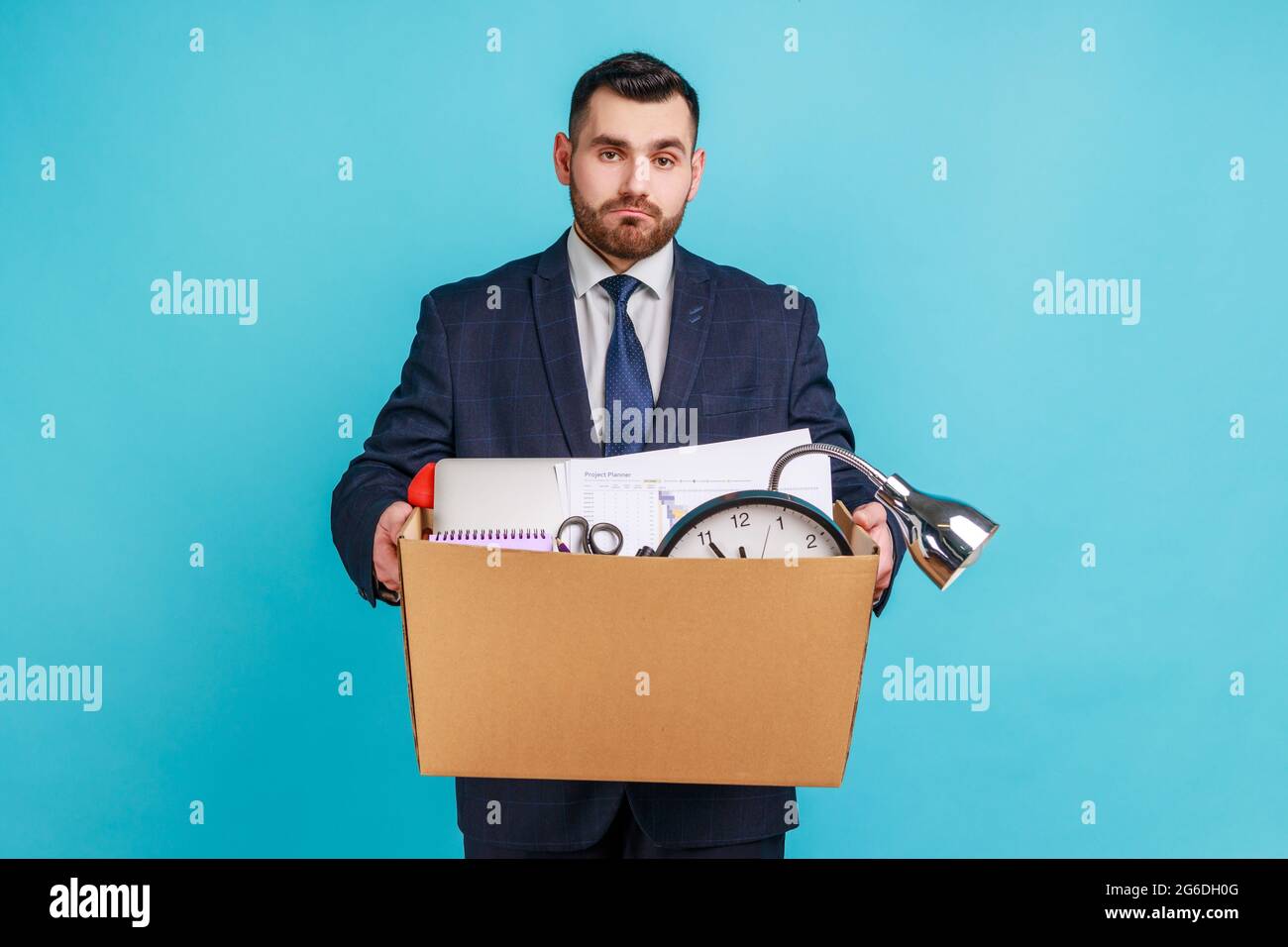 Portrait of sad depressed man employee in suit standing and holding in hands things in cardboard box, feeling sadness, dismissed from job. Indoor stud Stock Photo