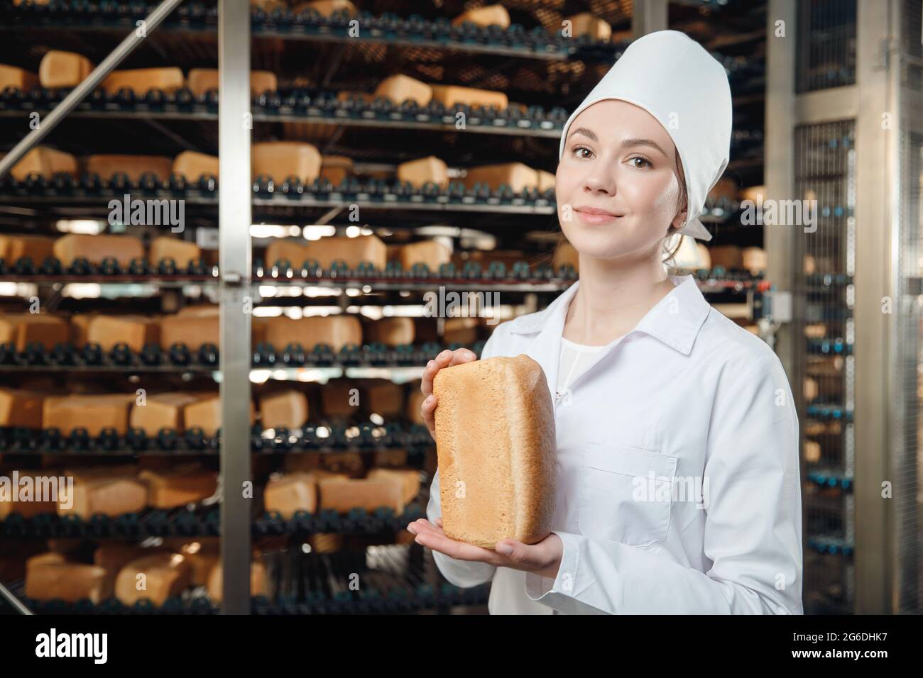 https://c8.alamy.com/comp/2G6DHK7/woman-baker-holding-fresh-bread-in-hands-on-background-automatic-conveyor-of-bakery-food-factory-2G6DHK7.jpg