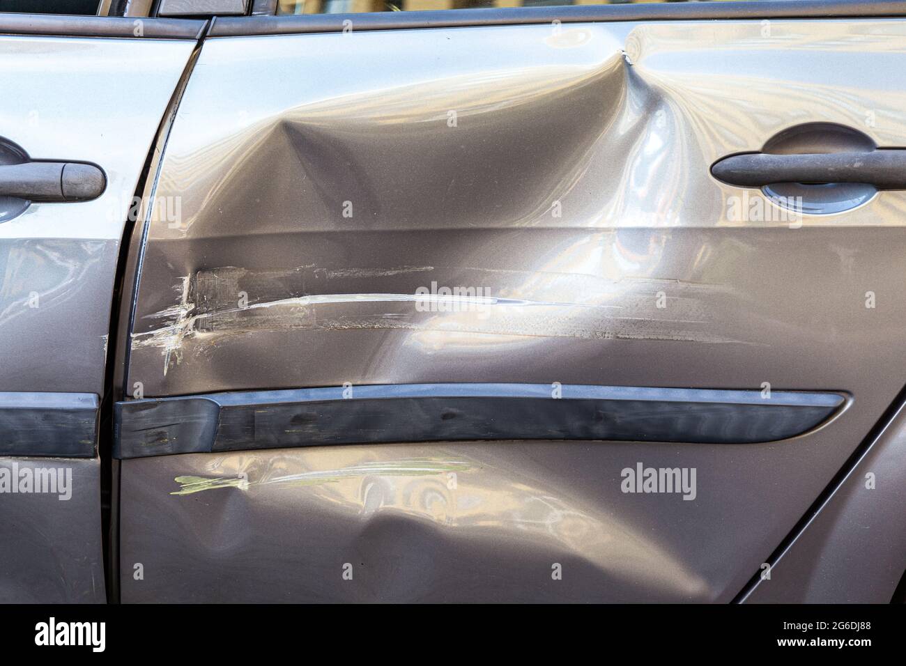 Closeup of damaged back door of car after accident on a road, dents and