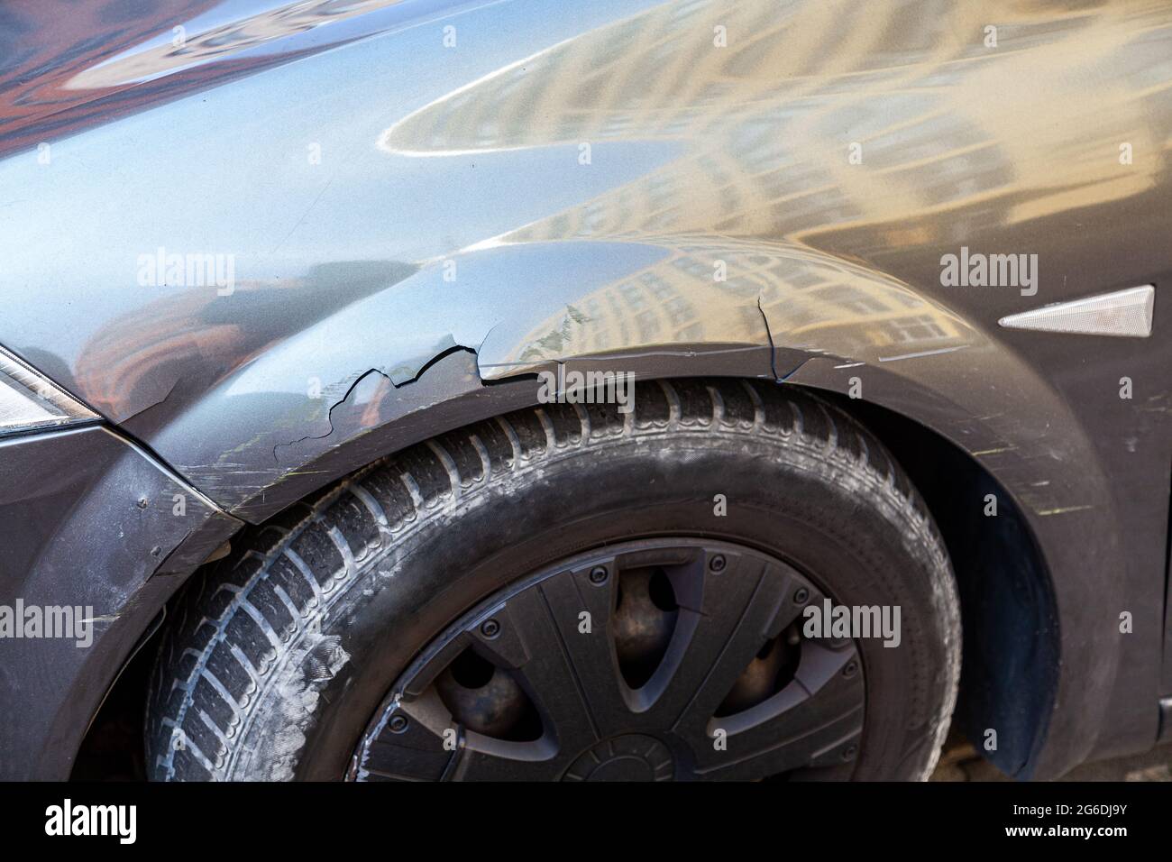 Closeup of side part of auto wheel and fender with cracks, dents and scratches after road accident, broken vehicle with destroyed auto body. Outdoor s Stock Photo