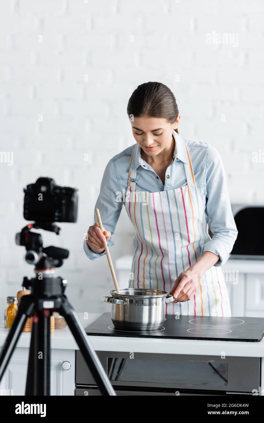 young culinary blogger preparing food in front of blurred digital camera Stock Photo