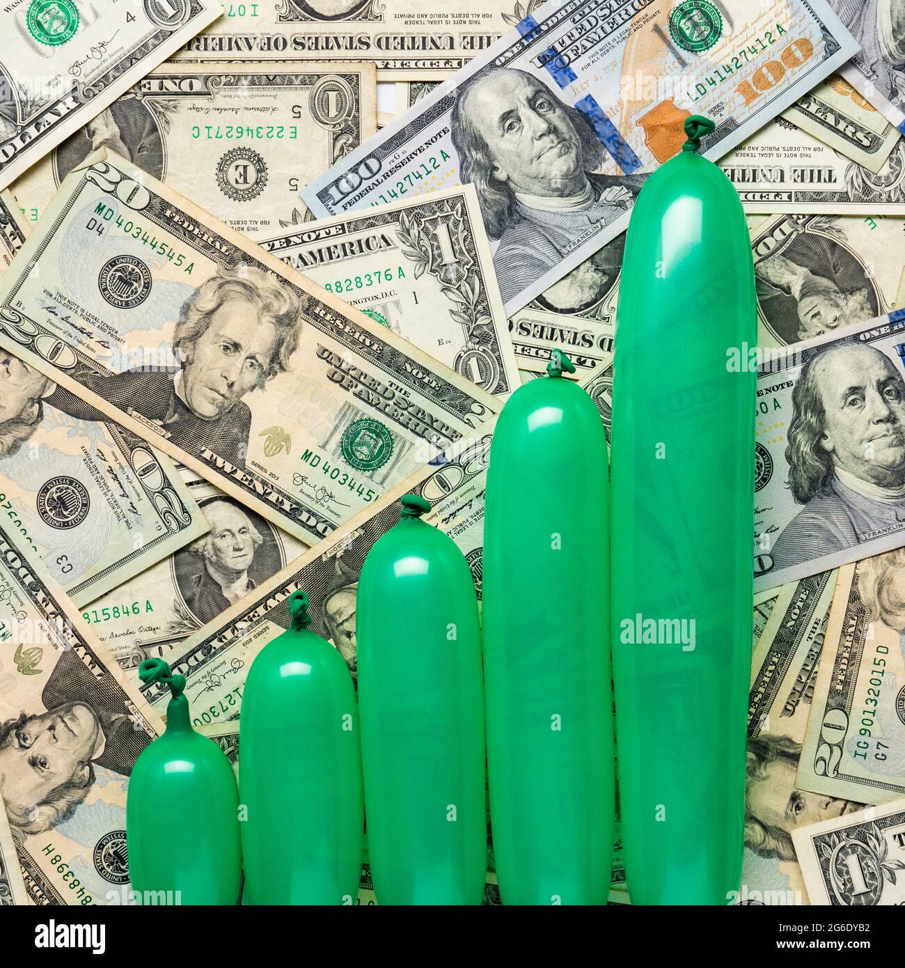 concept of inflation with green balloons inflated to varying amounts on a background on us cash Stock Photo