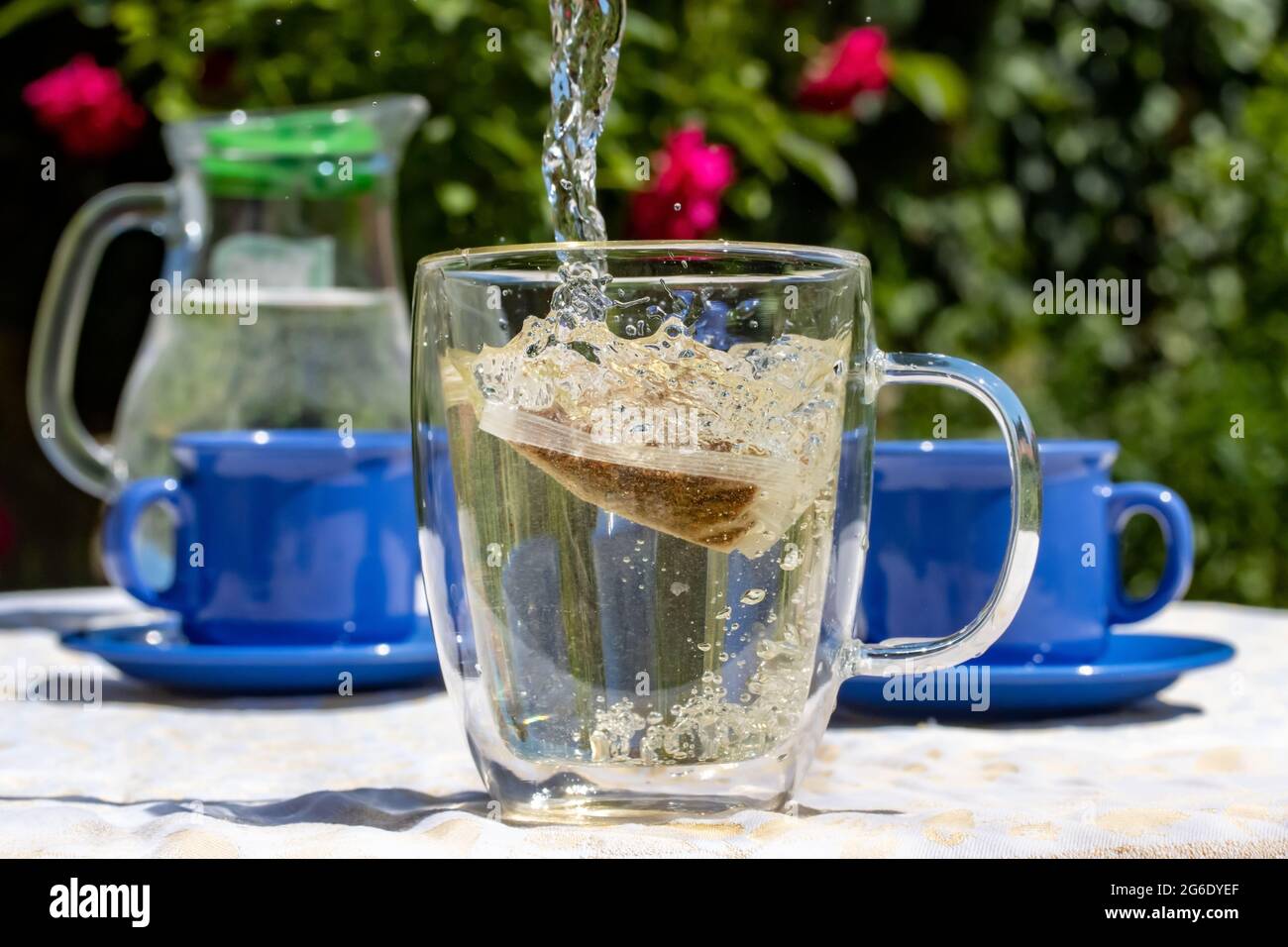 Water flows into a mug with a tea bag. A picnic in the summer garden ...