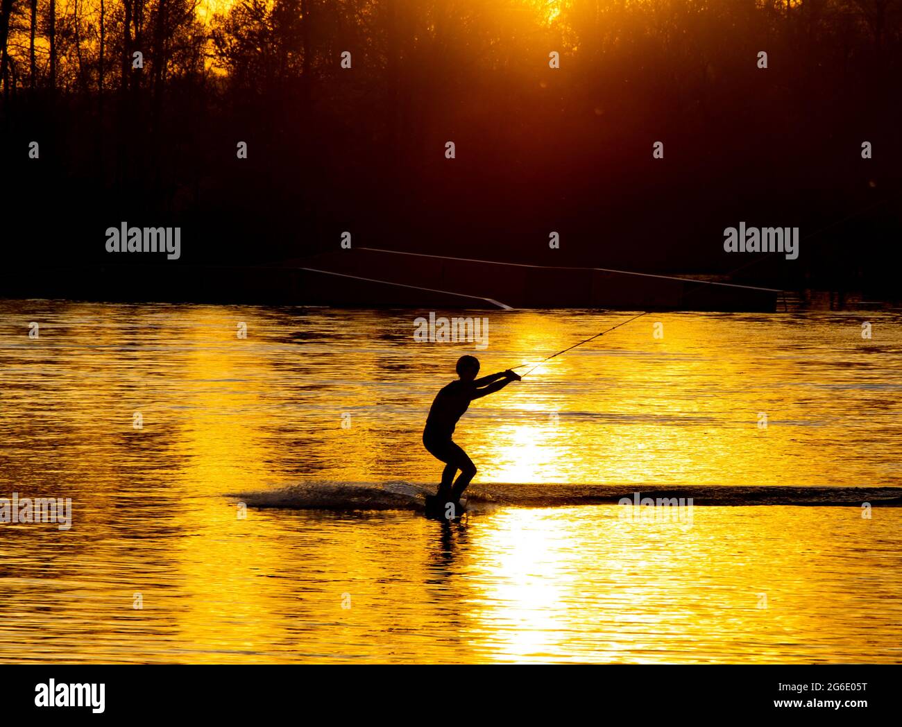 Silhouette of an athlete riding a water ski at sunset Stock Photo