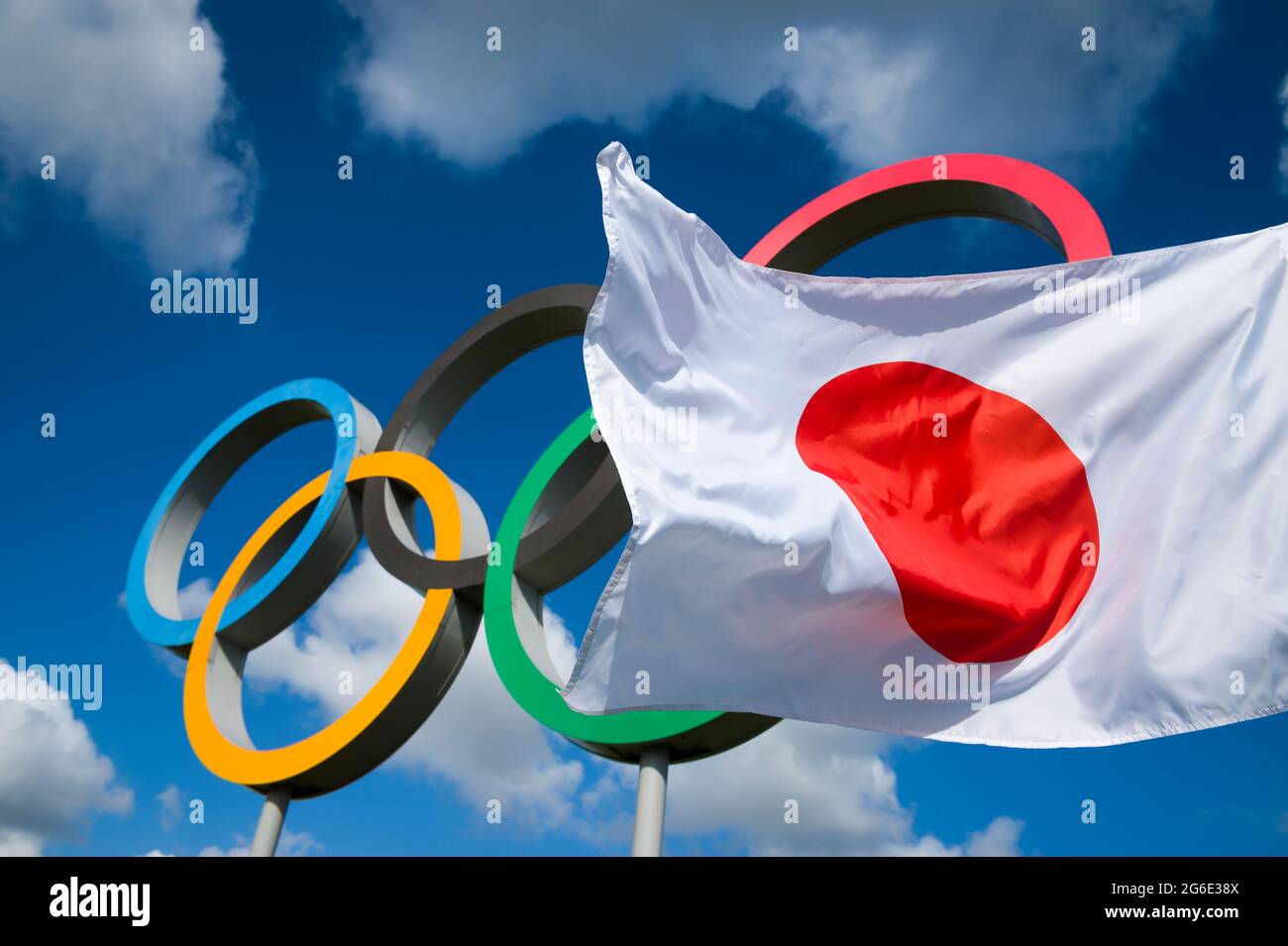 RIO DE JANEIRO - MARCH, 2016: A Japanese flag flutters in the wind in front of Olympic Rings standing under bright blue sky. Stock Photo