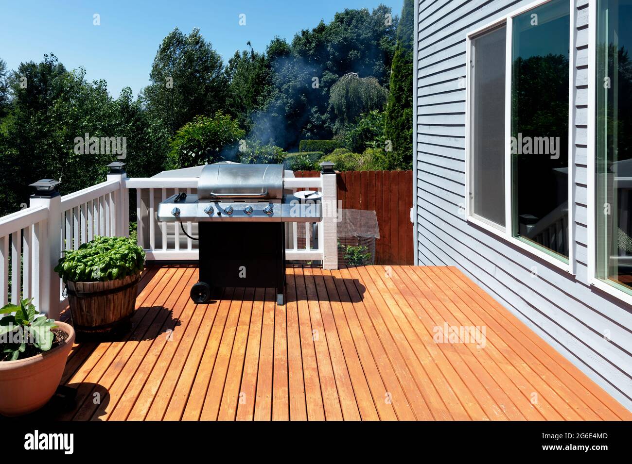 Large outdoor BBQ cooker with smoke coming out while on home wooden deck during summertime Stock Photo