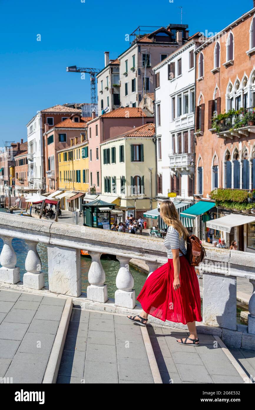 Young woman in red dress walking over Scalzi Bridge on the Grand Canal, Venice, Veneto, Italy Stock Photo