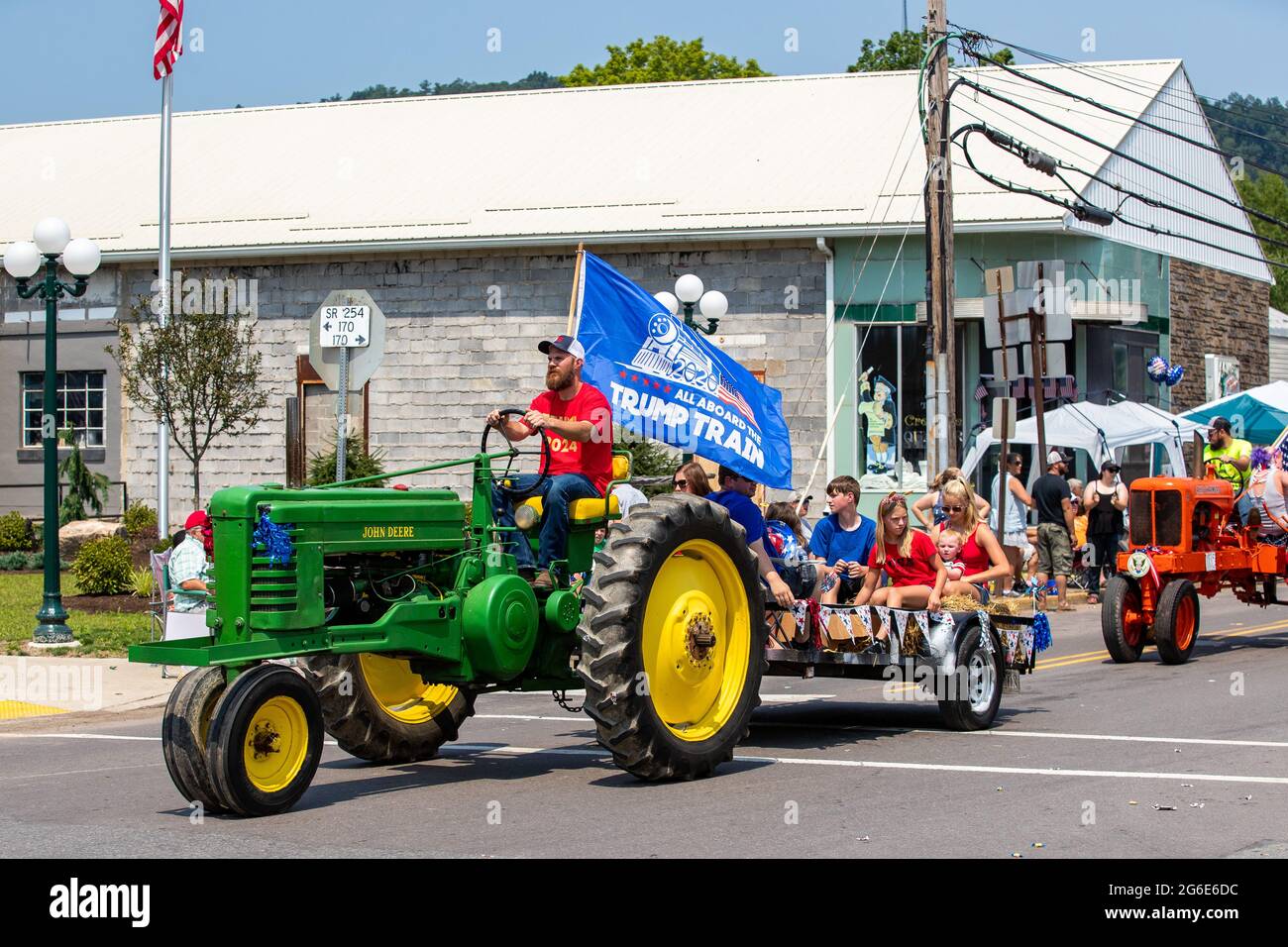 A man is seen driving a John Deere tractor with a Trump flag in the