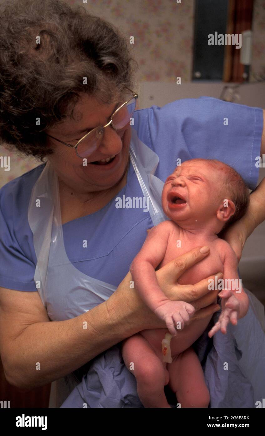 hospital midwife in delivery room holding up newborn baby boy Stock Photo