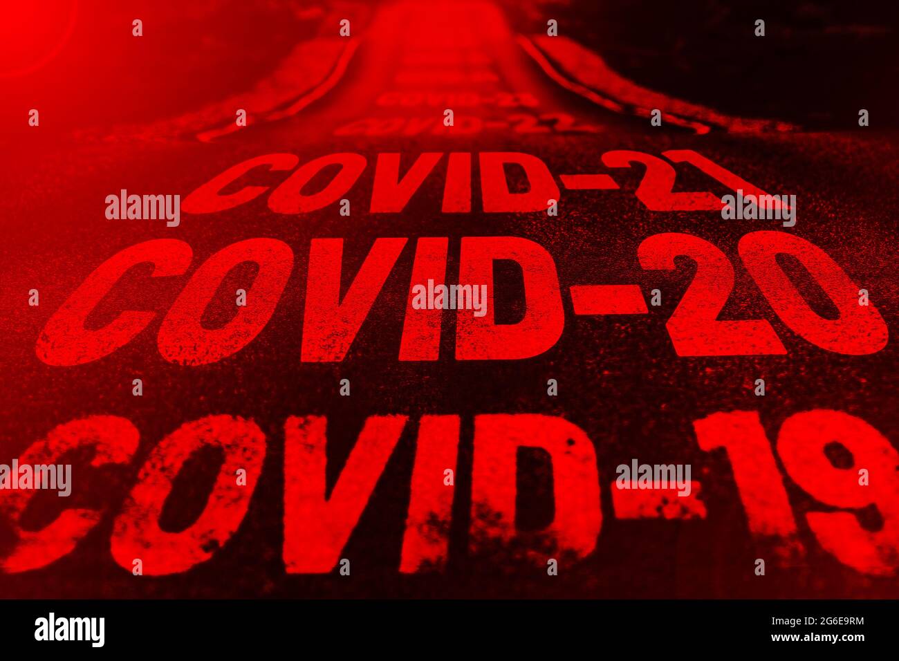 Deserted highway with the text COVID-19, COVID-20, COVID-21 and so on. The concept of new world pandemics. Red background Stock Photo