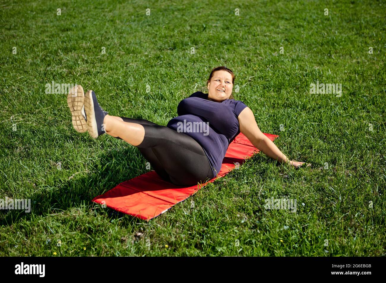 Leg lift exercise performed by body positive obese woman on lawn Stock Photo Alamy