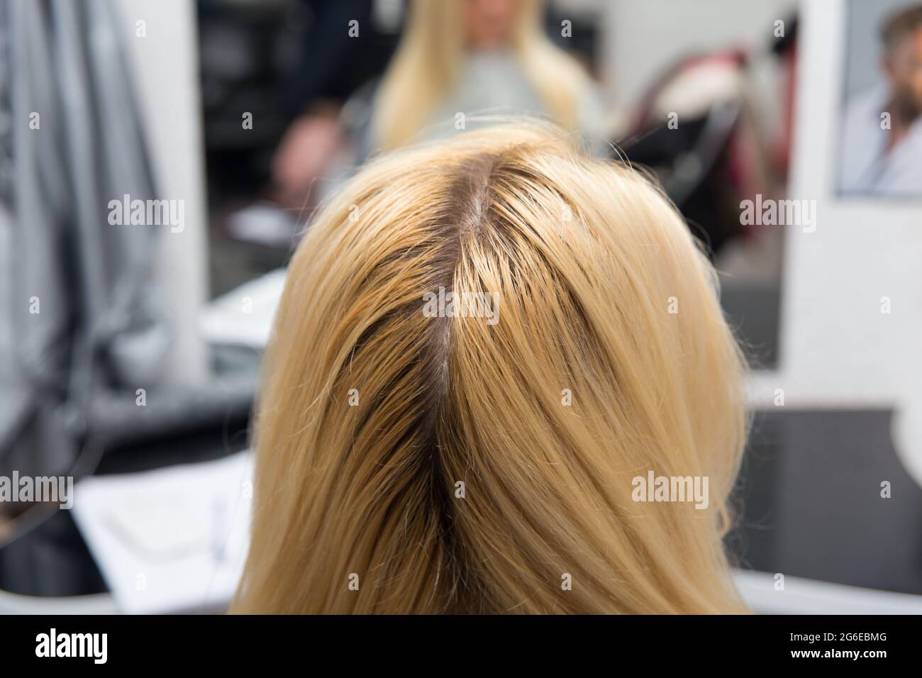 A hairdresser applies paint with a brush to a woman's hair in a beauty