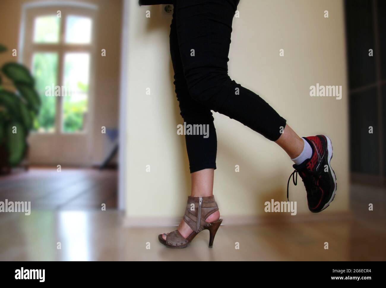 choosing shoes, sneakers versus high heels, one foot in high-heeled shoe  and one foot in sport shoes, woman wearing two different shoes Stock Photo  - Alamy