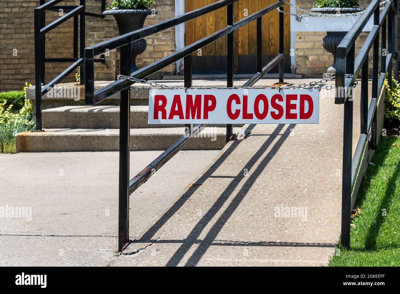 Red and white sign stating 'ramp closed'. Chained to black iron handrails. In front of church entrance. Stock Photo