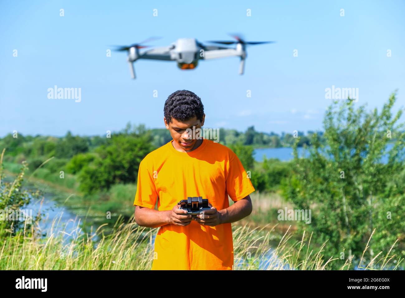African American man operating drone with controller in hands on the meadow Stock Photo