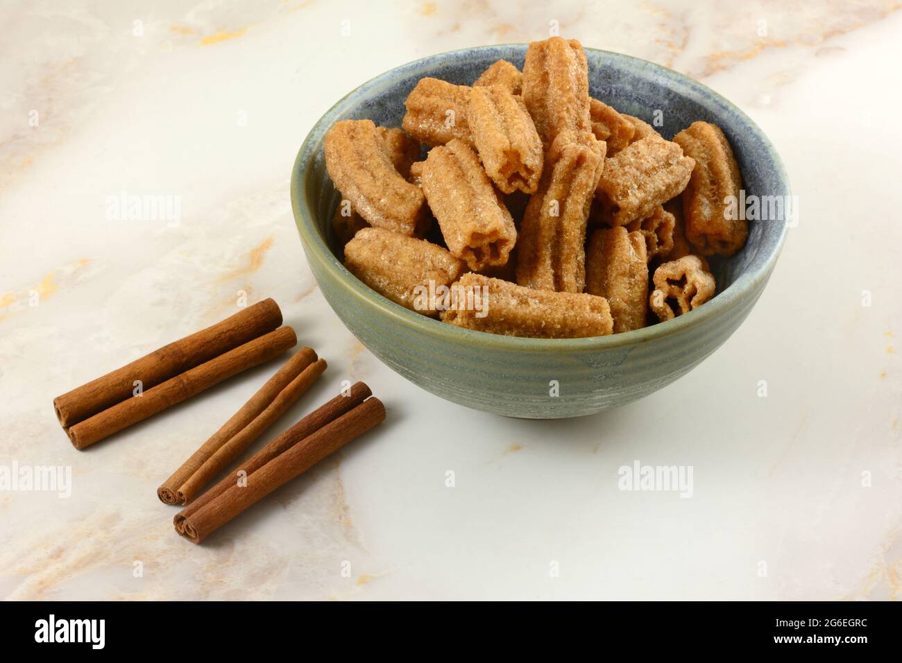 Cinnamon sugar churro snack in ceramic snack bowl with cinnamon sticks on table Stock Photo