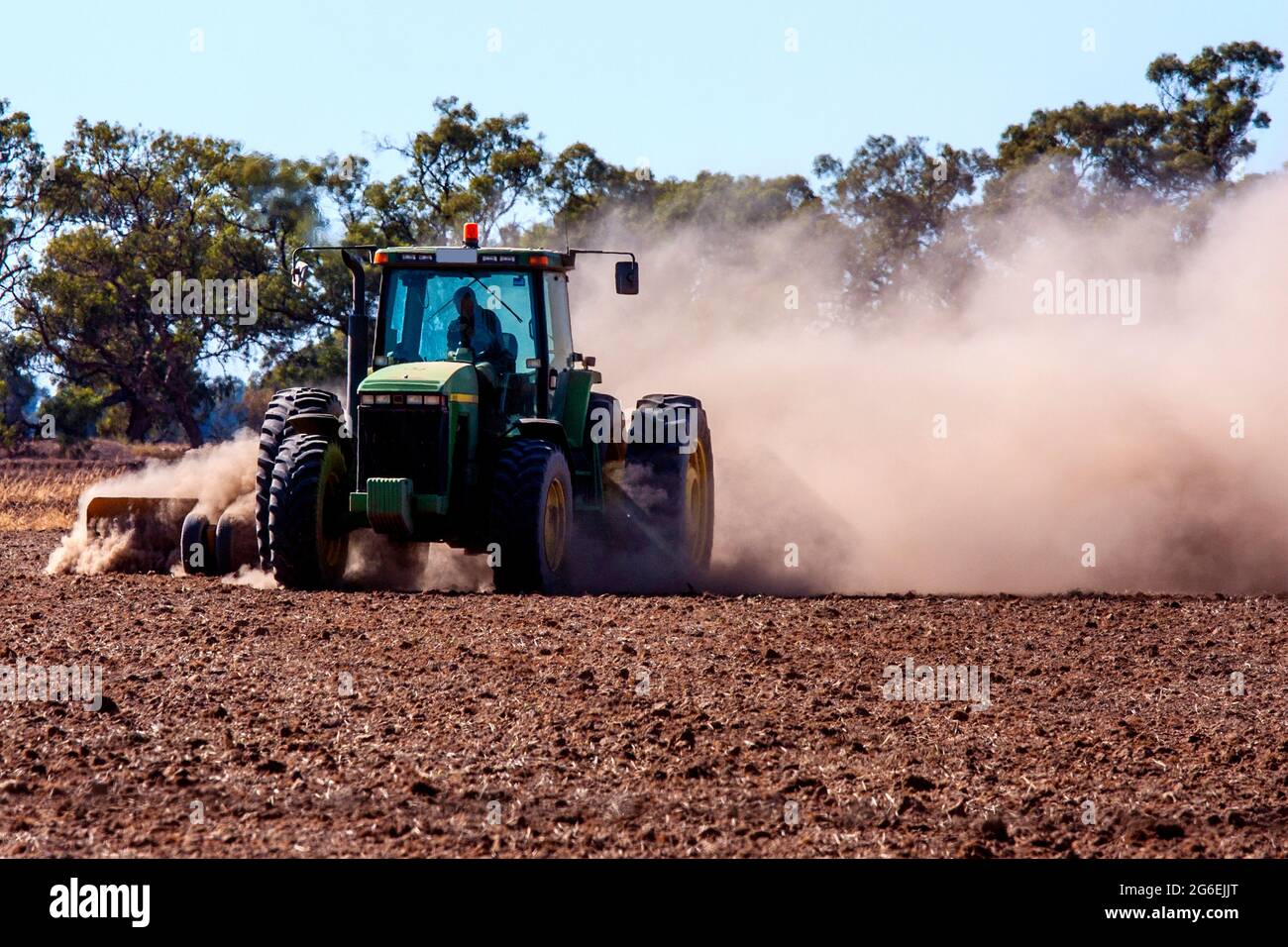 Tractor raises dust while ploughing drought stricken field in NSW Stock Photo