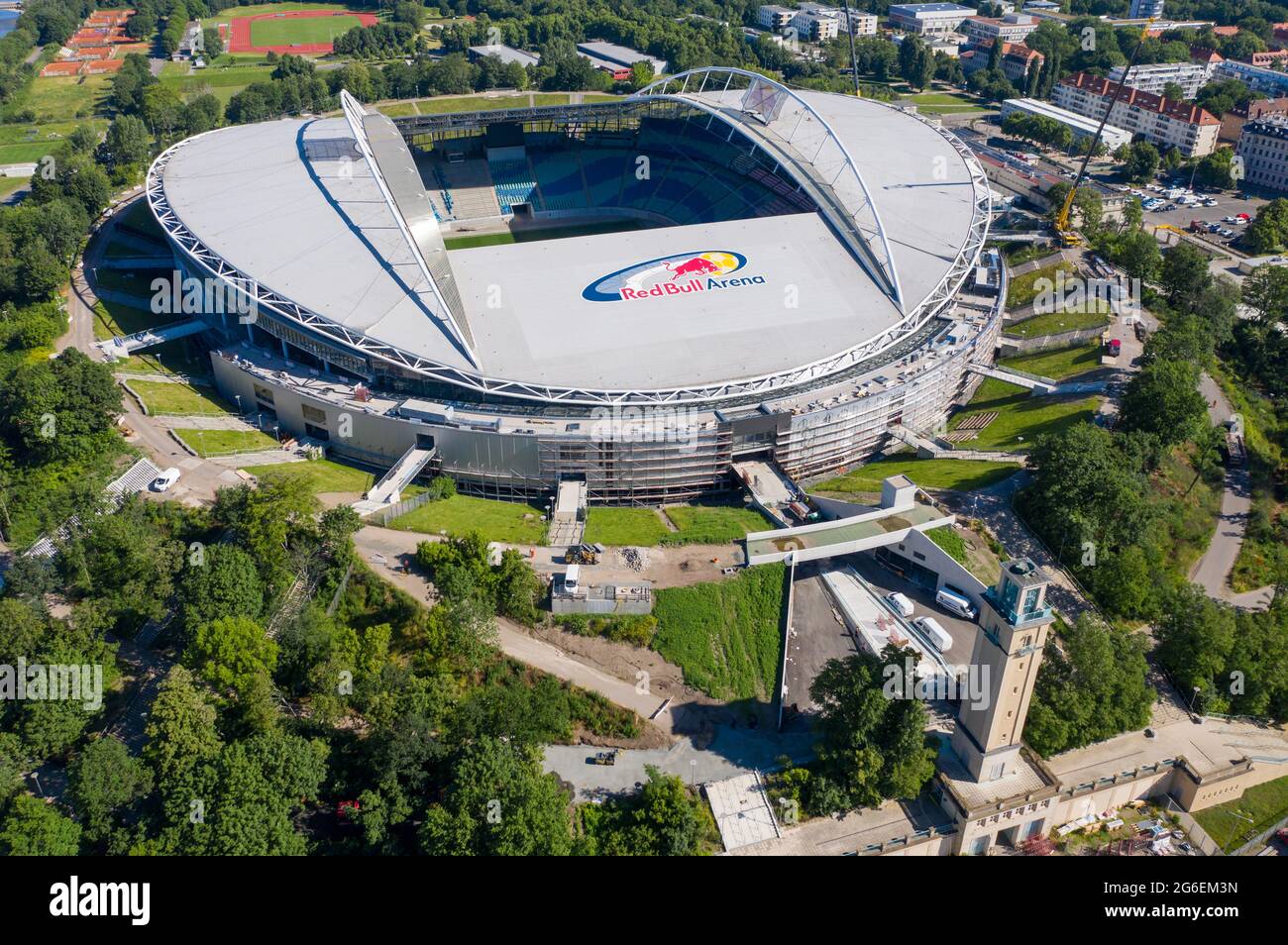 14 June 2021, Saxony, Leipzig: Football: Bundesliga, RB Leipzig. Two cranes are at the Red Bull Arena. The home ground of the Rasenballers is being rebuilt. The spectator capacity will increase from 42,558 to 47,069 in standing and seated areas. The outside of the stadium is enclosed with a soundproof facade. The embankment of the former Zentralstadion, which encompasses the arena, was cut open behind the historic bell tower to make room for a new entrance. RB Leipzig is investing a good 60 million euros in the conversion by 2022. (Aerial view with drone) Photo: Jan Woitas/dpa-Zentralbild/dpa Stock Photo