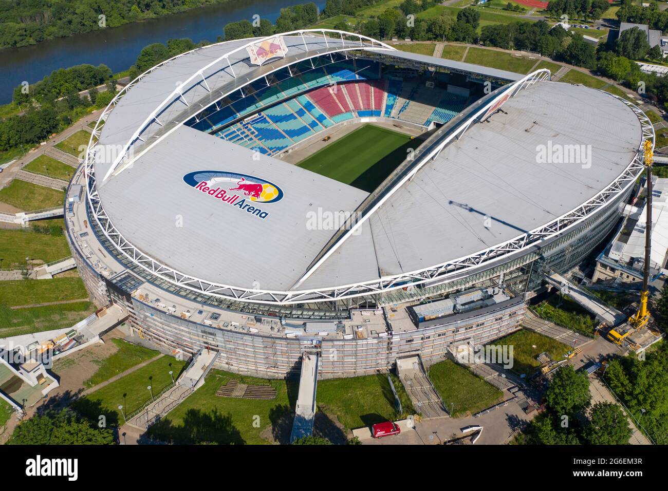 14 June 2021, Saxony, Leipzig: Football: Bundesliga, RB Leipzig. A crane stands at the Red Bull Arena. The home ground of the Rasenballers is being rebuilt. The spectator capacity will increase from 42,558 to 47,069 standing and seated. The outside of the stadium is enclosed with a soundproof facade. The embankment of the former Zentralstadion, which encompasses the arena, was cut open behind the historic bell tower to make room for a new entrance. RB Leipzig is investing a good 60 million euros in the conversion by 2022. (Aerial view with drone) Photo: Jan Woitas/dpa-Zentralbild/dpa Stock Photo