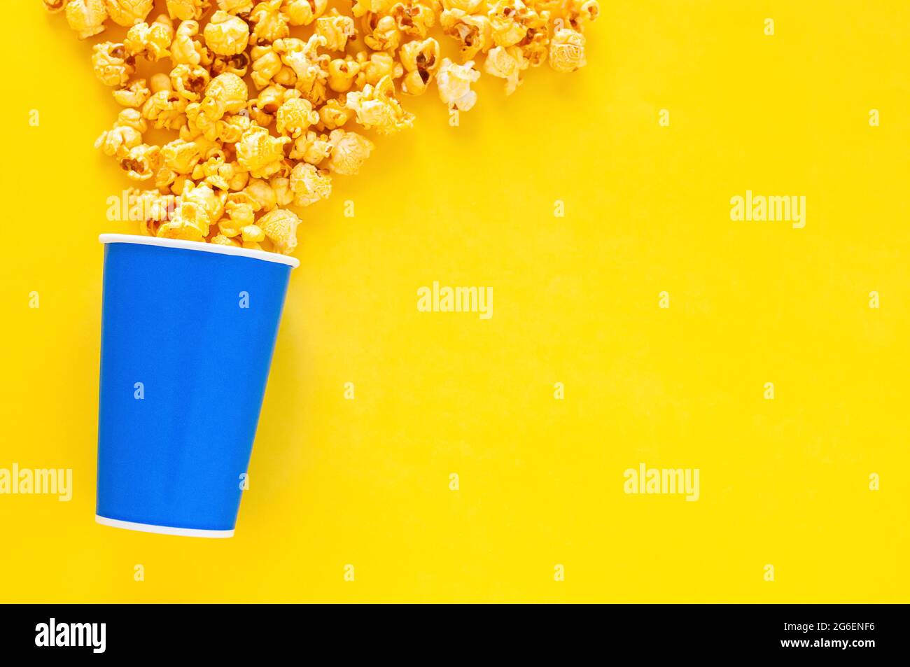 Sweet Caramel Popcorn in blue paper bucket on yellow background Stock