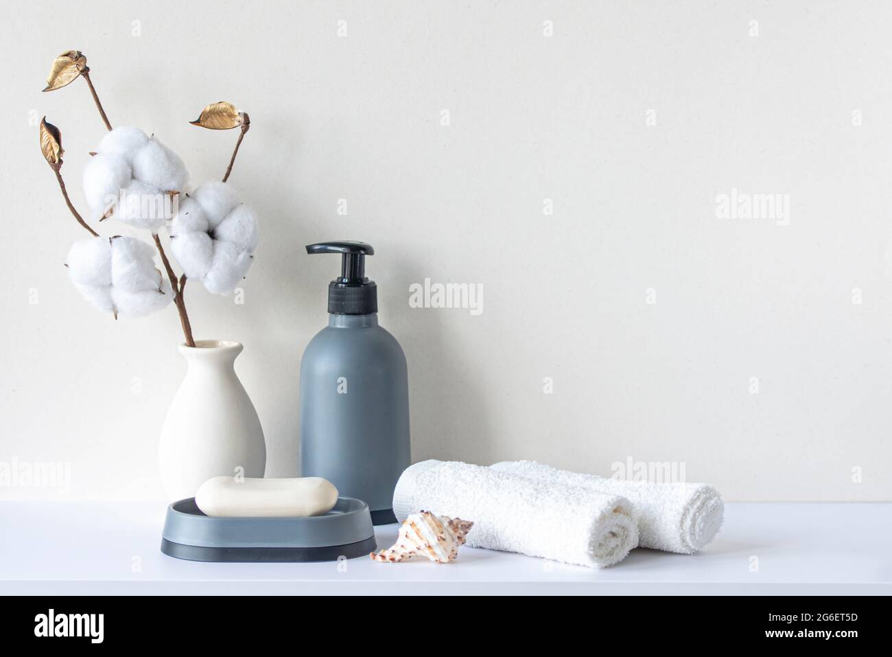 Bathroom interior in beige pastel tone. White shelf in bathroom with towels, soap, shampoo bottle, houseplant. Mockup with space for text. Minimal com Stock Photo