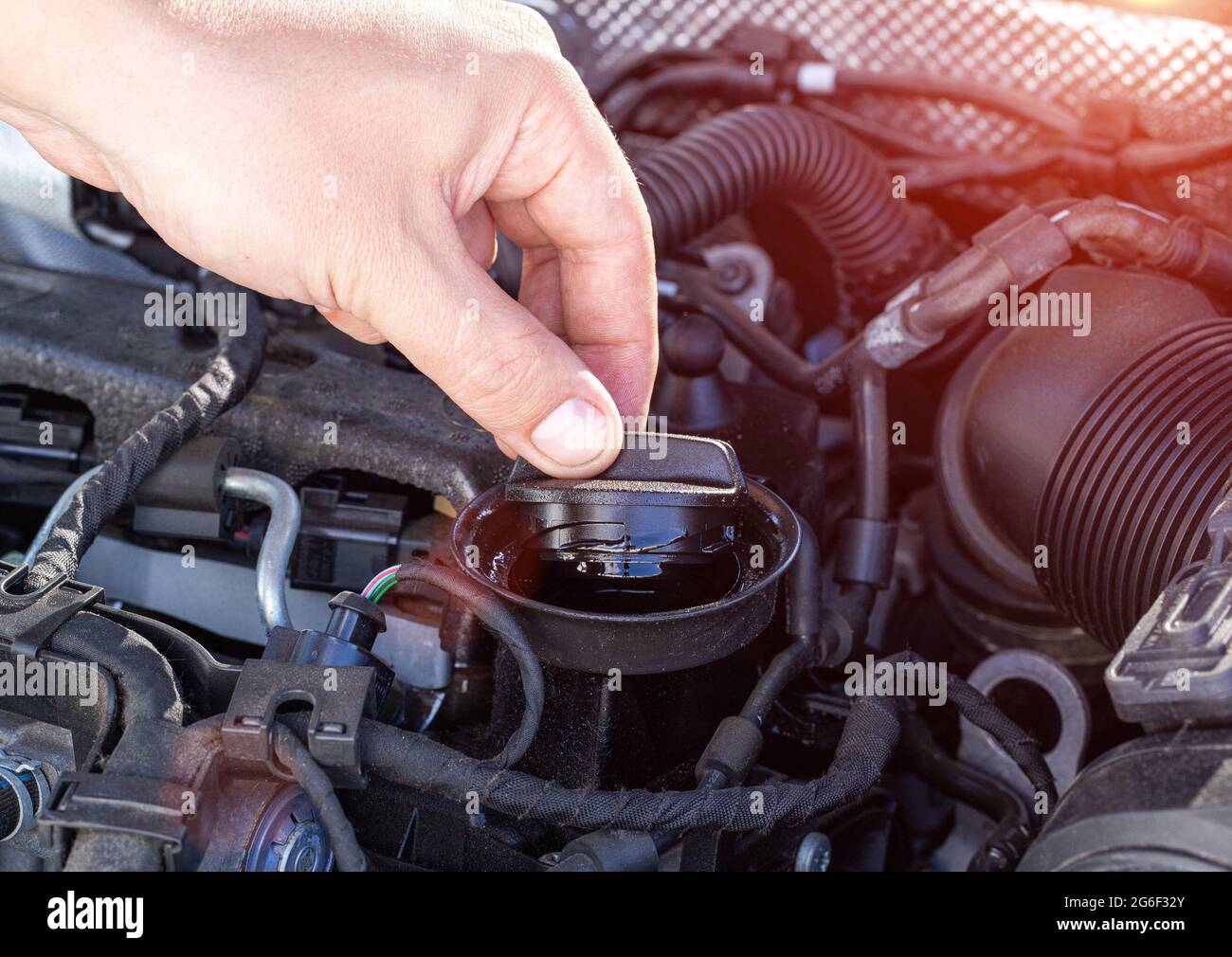 A man's hand unscrews the oil filler plug of a diesel engine to check