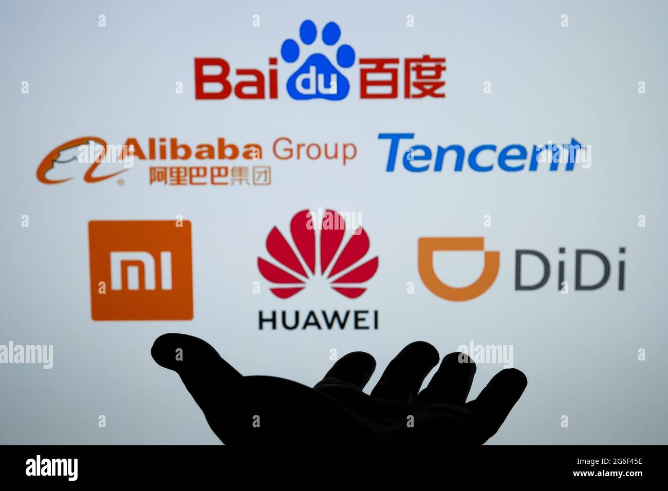 Silhouette of dark hand and blurred chinese Big Tech companies logos Baidu Alibaba Tencent Xiaomi Huawei Didi. Concept. Real photo, not a montage. Sta Stock Photo